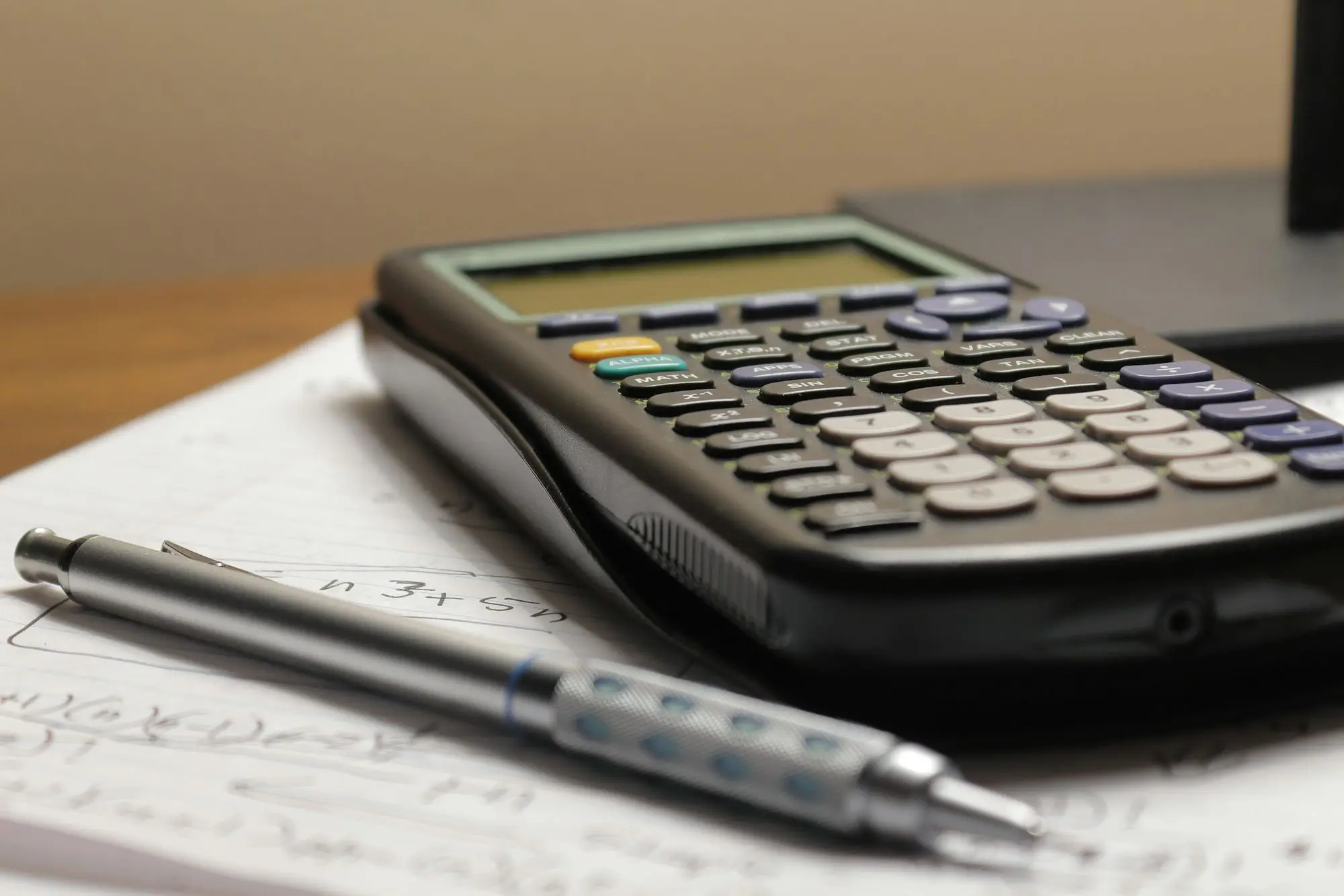 A calculator and pen on handwritten figures