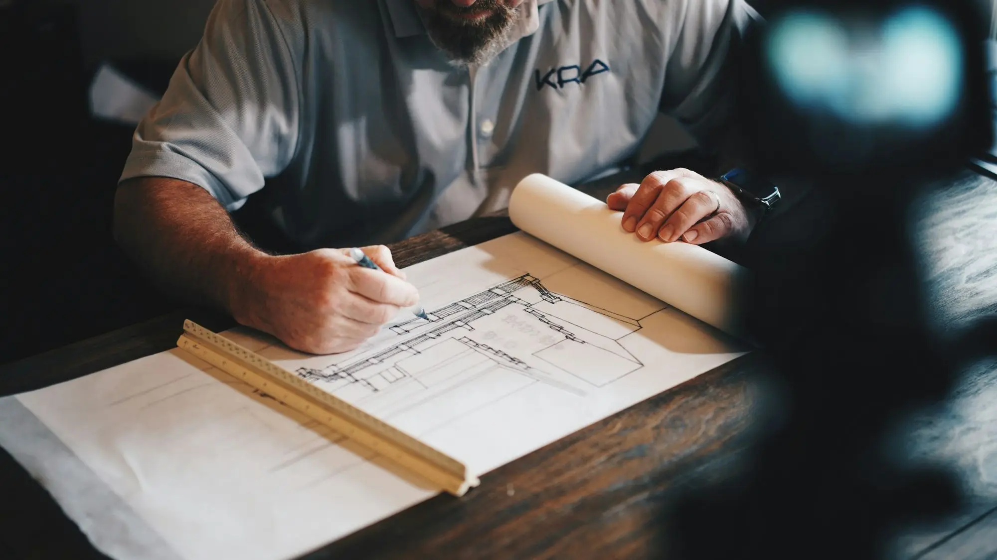 A designer drawing plans with a scale ruler